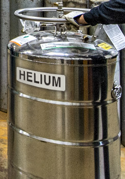 Photo of a person pushing a large tank of liquid helium