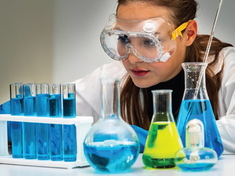 A photo of a female scientist with beakers