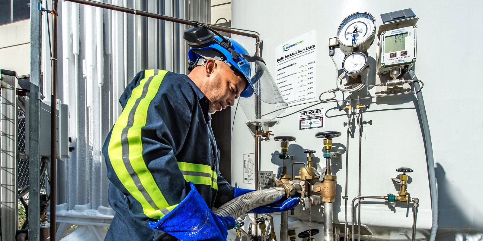 A photo of a Middlesex Gases employee checking readings on a tank