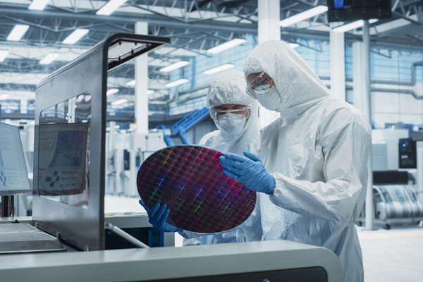 Engineers inspecting a silicon wafer used in semiconductor manufacturing