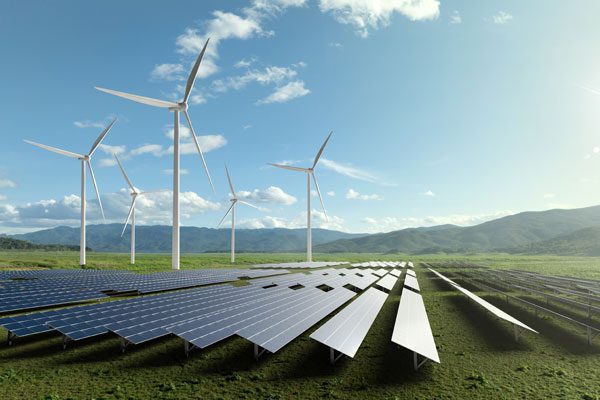 Clean energy facility featuring solar panels and wind turbines in an open field