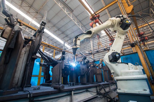 Robotic arm performing automated welding in an industrial manufacturing facility
