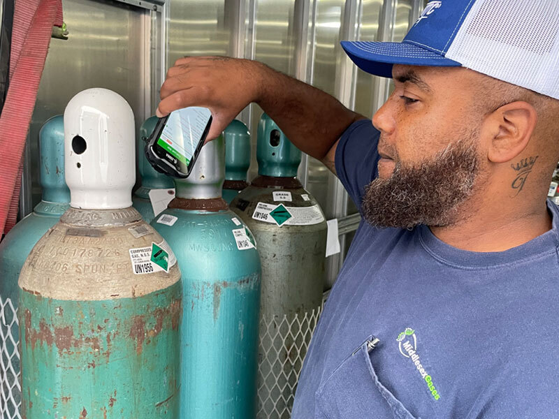 Middlesex Gases employee using a mobile device to track compressed gas cylinders in storage